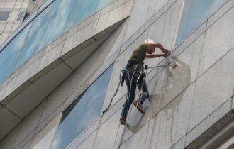 Mężczyzna pracujący przy elewacji budynku na wysokościach