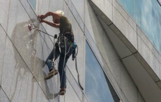 mężczyzna w dostępie linowym na elewacji budynku