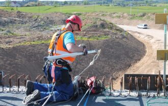 Mężczyzna w kasku i kamizelce pracuje na dachu